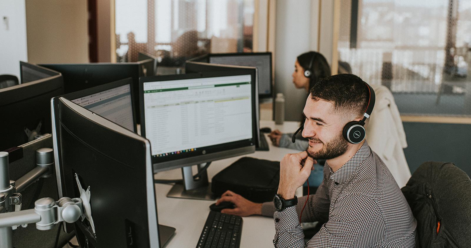 Male Smiling While Working on Computer and Phone