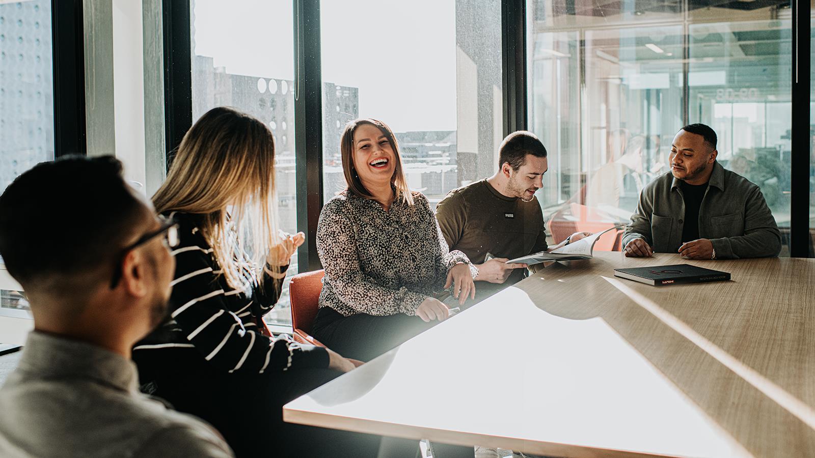 Team Laughing and Discussing Around Table