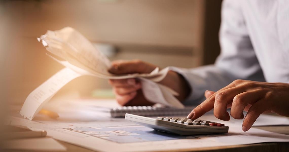 Closeup Economist Using Calculator While Going Through Bills Taxes Office