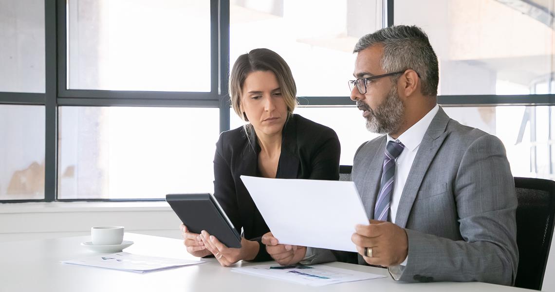 Company Leaders Analyzing Reports Two Business Colleagues Sitting Together Looking Document Holding Tablet Talking Medium Shot Communication Concept